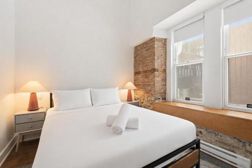 a bedroom with a large white bed and windows at Meramont Hotel Downtown in Montreal