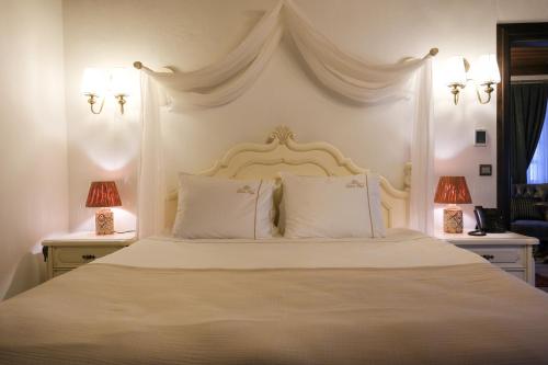 a bedroom with a white bed with two lamps at Gülce Köşk Otel & Restaurant in Amasya
