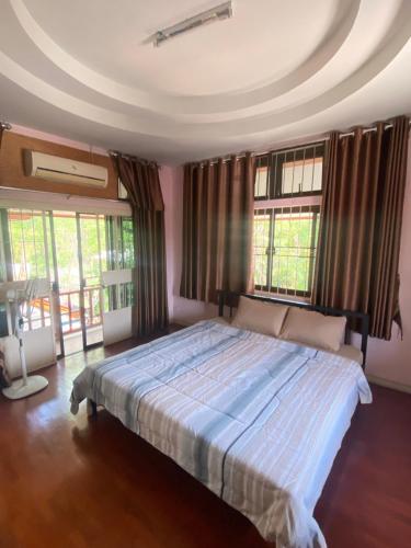 a bedroom with a large bed in a room with windows at Wandeehomehost in Chiang Mai