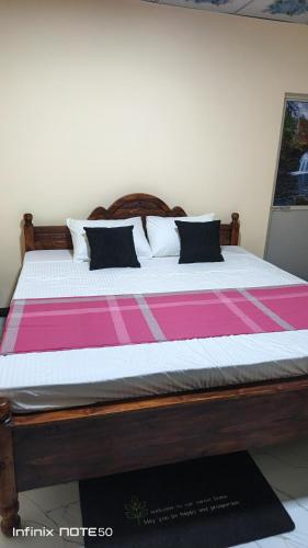 a bed with pink and white sheets and pillows at Ashi Retreat in Dambulla