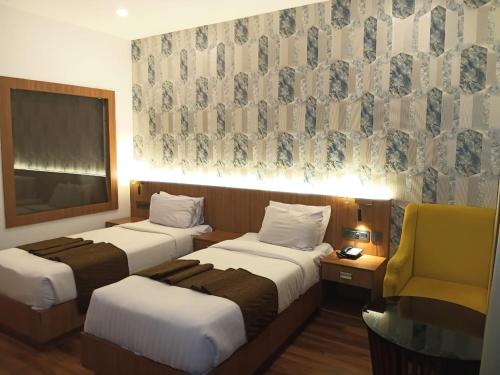 a hotel room with two beds and a chair at SKY PENTA RESIDENCY in Iritti