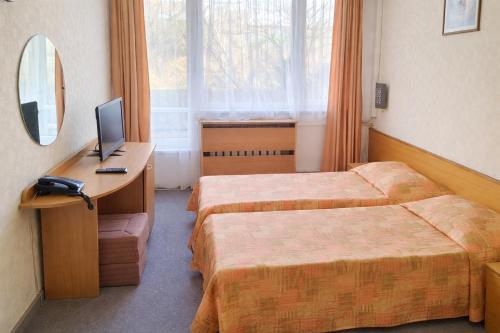 a hotel room with two beds and a desk with a computer at Neptune Hotel in Saints Constantine and Helena