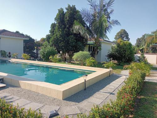 a swimming pool in a yard with trees and a house at TRANQUILITY Resort in Nong Prue