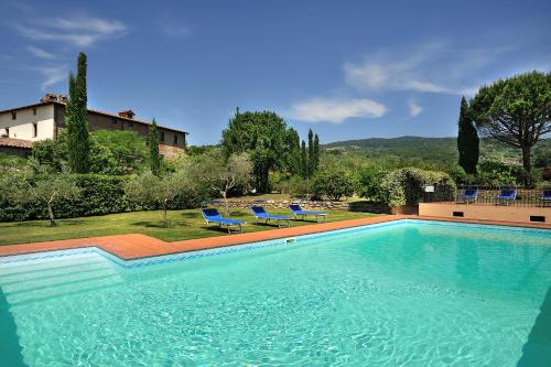 a large swimming pool with blue chairs and a house at La Fattoria del Rio di Sopra - Agriturismo Baldeschi in Tuoro sul Trasimeno