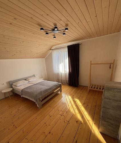 a bedroom with a bed and a wooden ceiling at Котедж HOLIDAY HOUSE in Yablunytsya