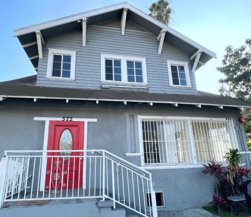 a gray house with a red door and stairs at Vernon Homes for the Soul in Los Angeles