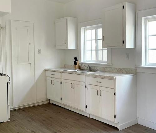 a white kitchen with white cabinets and a sink at Vernon Homes for the Soul in Los Angeles