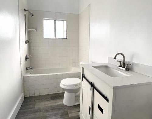 a white bathroom with a toilet and a sink at Vernon Homes for the Soul in Los Angeles