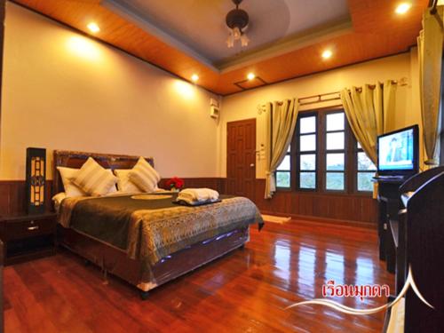 a bedroom with a bed and a flat screen tv at บ้านไร่คุณนาย in Ban Sap Bon