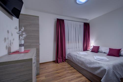 a bedroom with a bed and a window with red curtains at Willa Świderka in Kościelisko