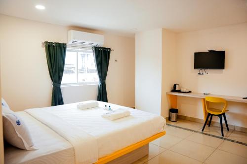 a bedroom with a bed and a desk and a television at Global Inn & Suites in Mangalore