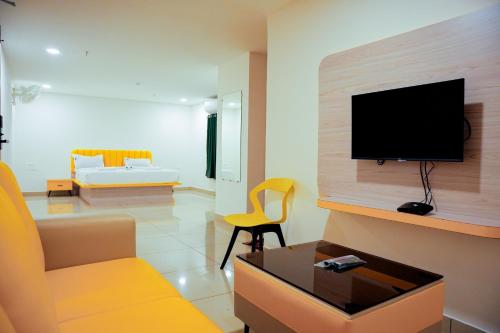 a living room with a couch and a tv on a wall at Global Inn & Suites in Mangalore