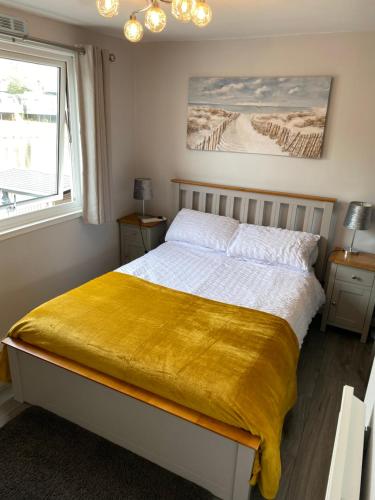 a bedroom with a bed with a yellow blanket on it at Lakeside Lodge 84 in Caeathro