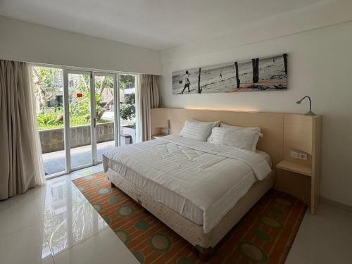a bedroom with a bed and a large window at New Jimbaran Hotel in Ungasan