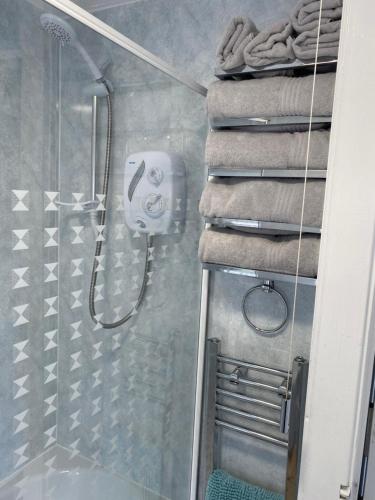 a bathroom with a shower with a stack of towels at Lakeside Lodge 84 in Caeathro