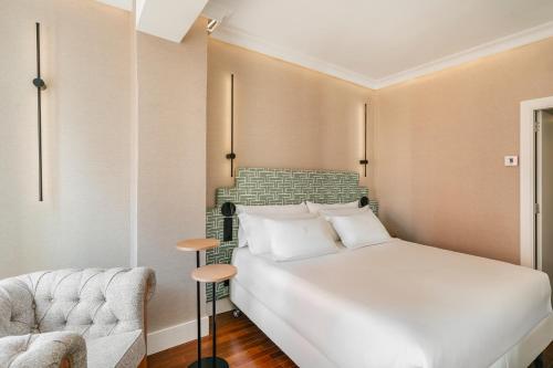 a bedroom with a white bed and a chair at Vincci Soma in Madrid