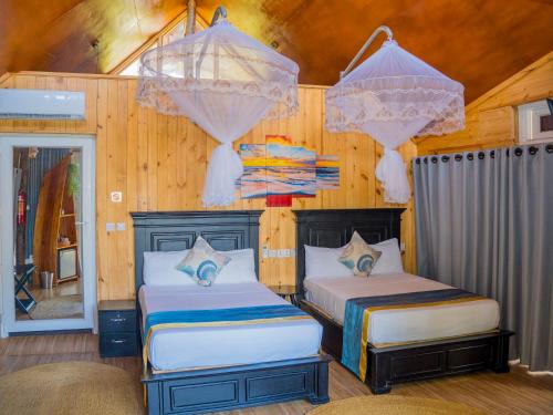 two beds in a room with wooden walls at Sea Eagle Oceanfront in Buyuni