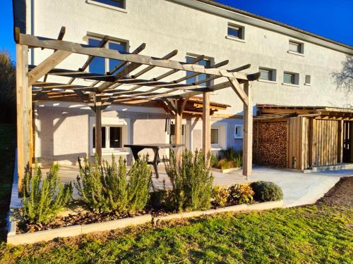 a wooden pergola in front of a building at L'atelier in Sugères