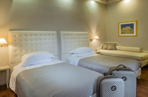 a hotel room with two beds and a suitcase at Hotel Vittoria in Faenza