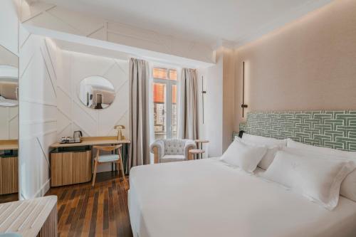 a hotel room with a white bed and a desk at Vincci Soma in Madrid