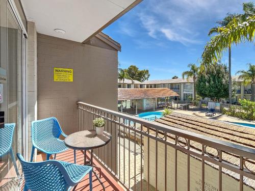 a balcony with a table and chairs and a pool at Charming Studio Apartment in Mandurah in Mandurah