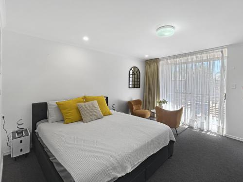 a bedroom with a large bed with yellow pillows at Charming Studio Apartment in Mandurah in Mandurah