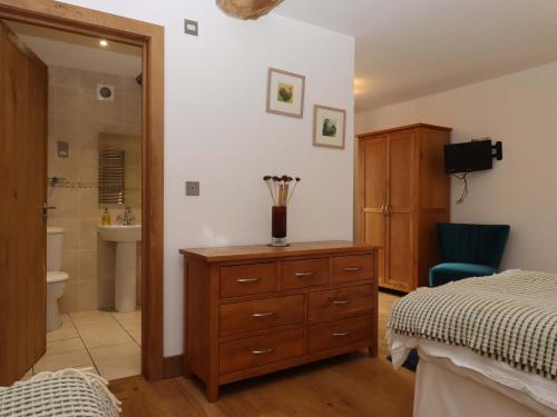 a bedroom with a bed and a dresser and a bathroom at Swallows Reach in Totnes