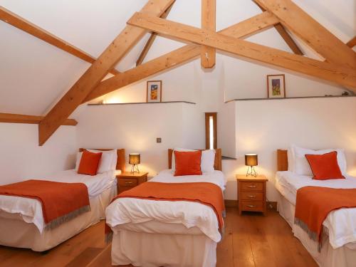 two beds in a room with wooden ceilings at Swallows Reach in Totnes