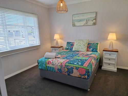 a bedroom with a bed and two lamps and a window at South Bunbury Beach Shack in Bunbury