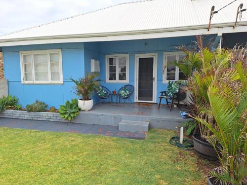 a blue house with two chairs on the front porch at South Bunbury Beach Shack in Bunbury