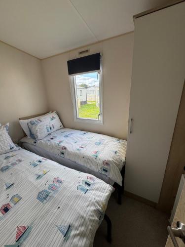 two beds in a small room with a window at Captain's Cabin - Brixham - with designated parking in Brixham