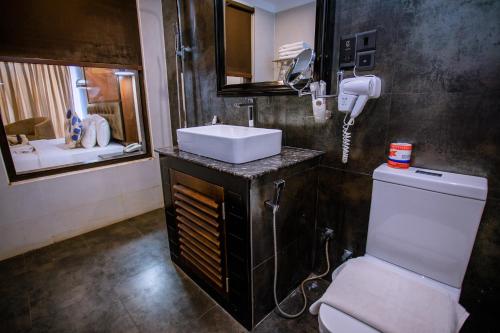 a bathroom with a sink and a toilet and a mirror at Emerald Bay Resort Mirissa in Mirissa