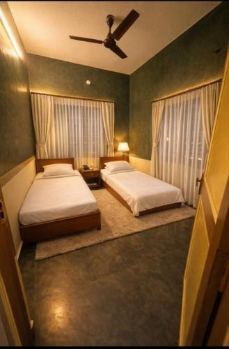 a bedroom with two beds and a ceiling fan at Gravity Groups Blue Lagoon Villa in Kuilapayam