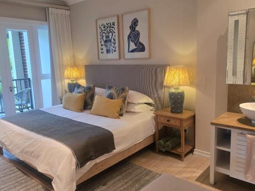 a bedroom with a bed with two lamps and a balcony at Eden Island Gem in Eden Island