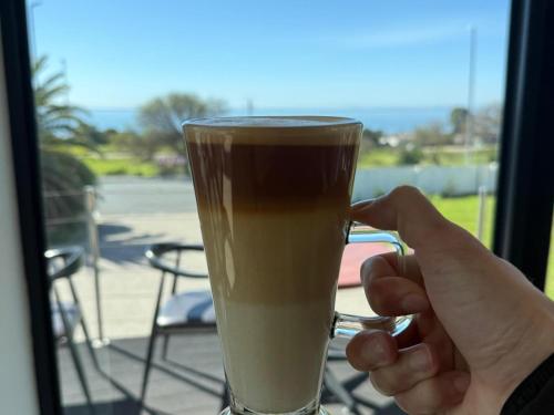 a person is holding up a glass of coffee at St Helena Bay Hotel in St. Helena Bay