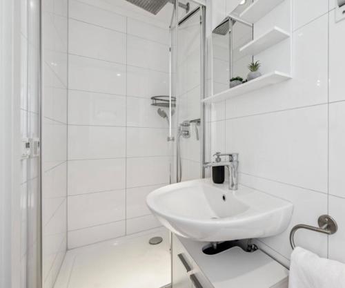 a white bathroom with a sink and a shower at Prime Host Balcony Apartment in Karlsruhe