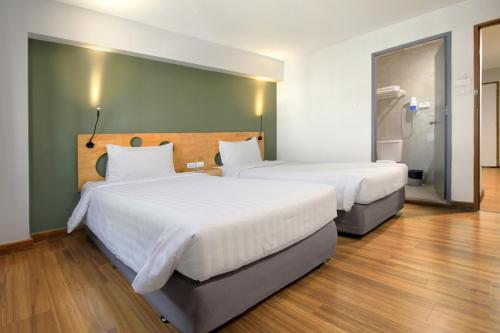 two beds in a hotel room with a bathroom at Mybed Sathorn Hotel in Bangkok