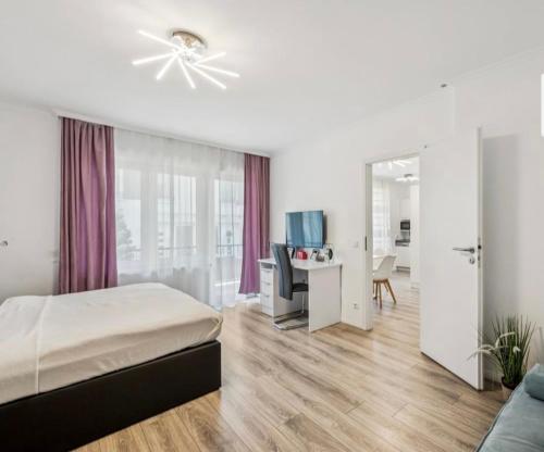 a bedroom with a bed and a desk with a computer at Prime Host Balcony Apartment in Karlsruhe