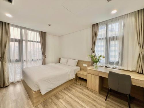 a bedroom with a bed and a desk and windows at GEM Hotel And Residence in Hanoi