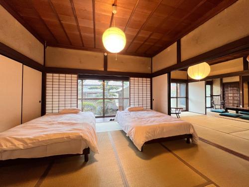 a bedroom with two beds and a large window at 瀬戸内海を望む庭付き古民家サウナ宿 一棟貸切 in Takamatsu