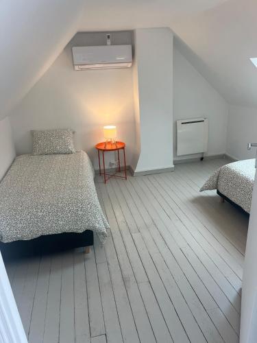 a bedroom with two beds and a table with a lamp at La Renardière in Foreste