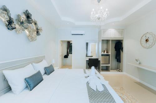 a white bedroom with a large white bed and a chandelier at BB Le Garden in Ban Thum