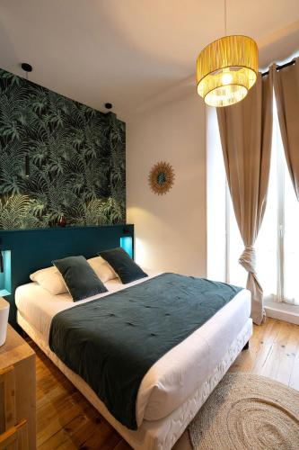 a bedroom with a large bed with a green headboard at Hotel de La Paix in La Rochelle