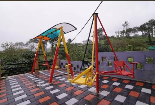 a playground with colorful swings on a roof at Heritage Vagamon Cottages in Idukki