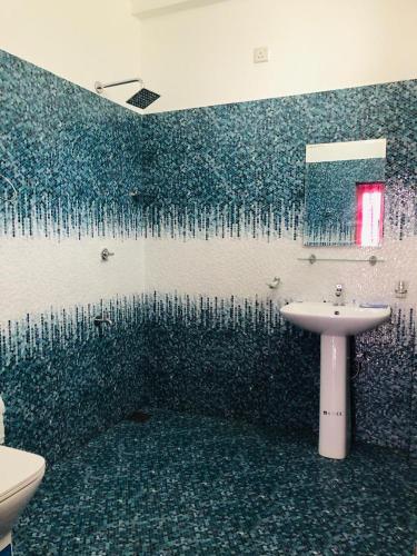 a bathroom with a blue tiled wall with a sink at Ruk Mountain Hotel in Kengalla