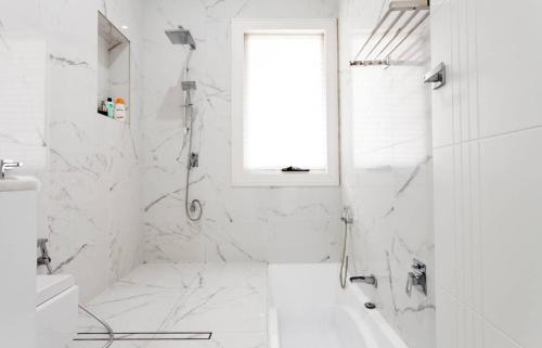 a white bathroom with a tub and a window at Relax and Retreat Studio Flat in Glenwood