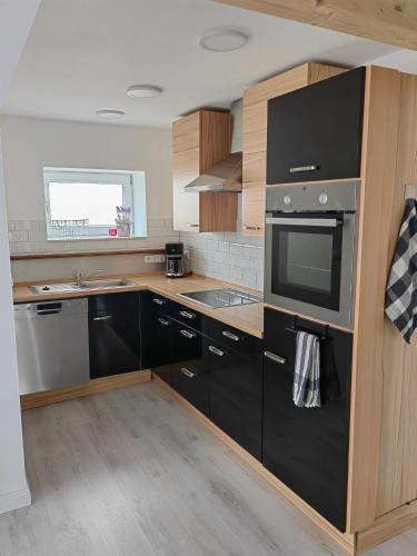 eine Küche mit schwarzen Geräten und Holzschränken in der Unterkunft Appartment Frieda in Raduhn