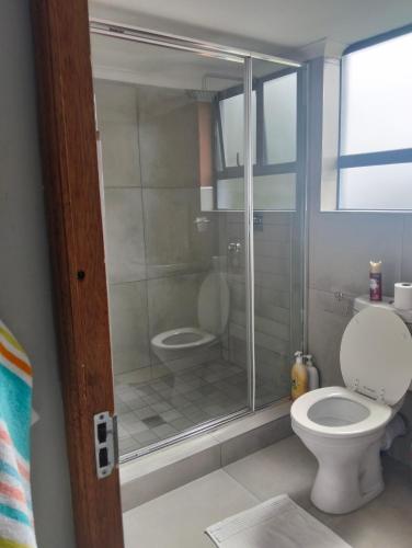 a bathroom with a toilet and a glass shower at Goodman's Guest home in Nelspruit