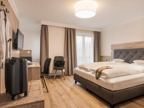 a bedroom with a bed and a desk and a tv at Hotel Finkenbergerhof in Finkenberg