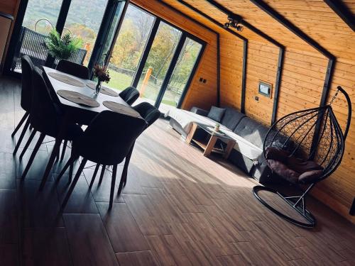 a dining table and chairs in a room with windows at Cabana Muncelus in Lupşa